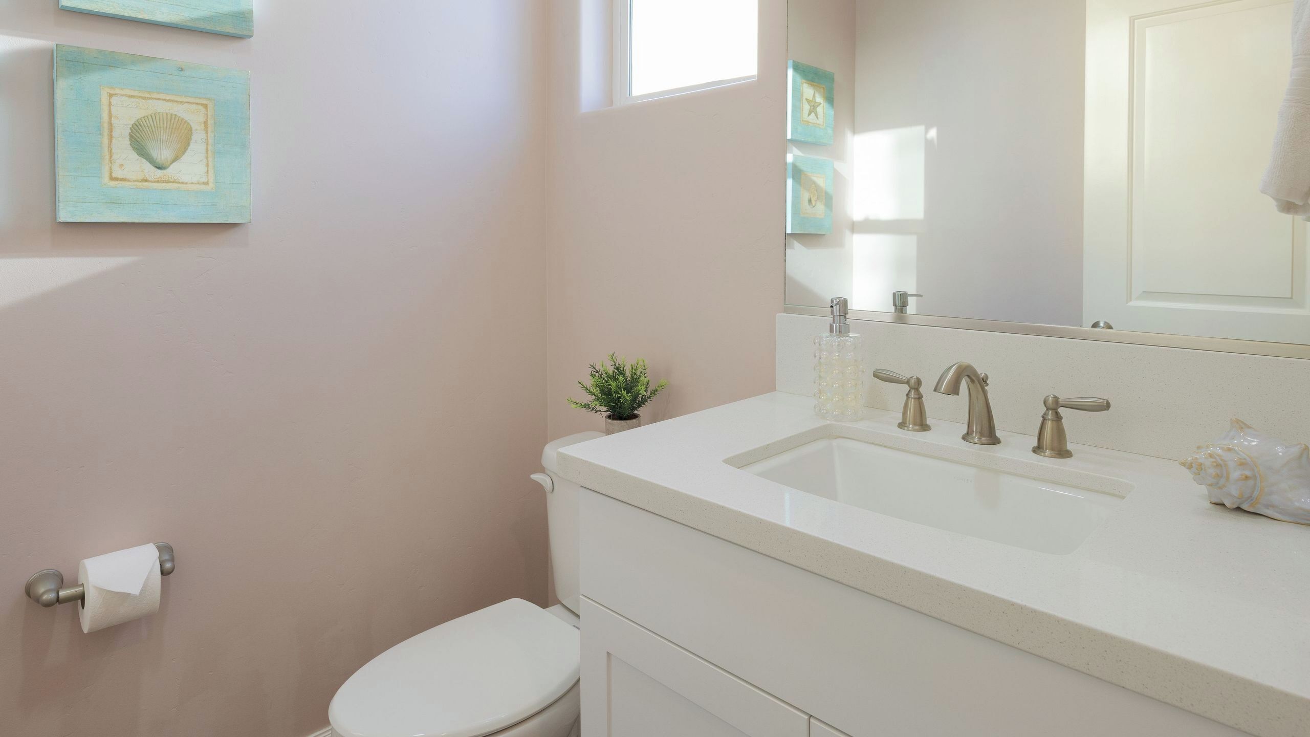 A bathroom with a toilet, sink, and mirror.