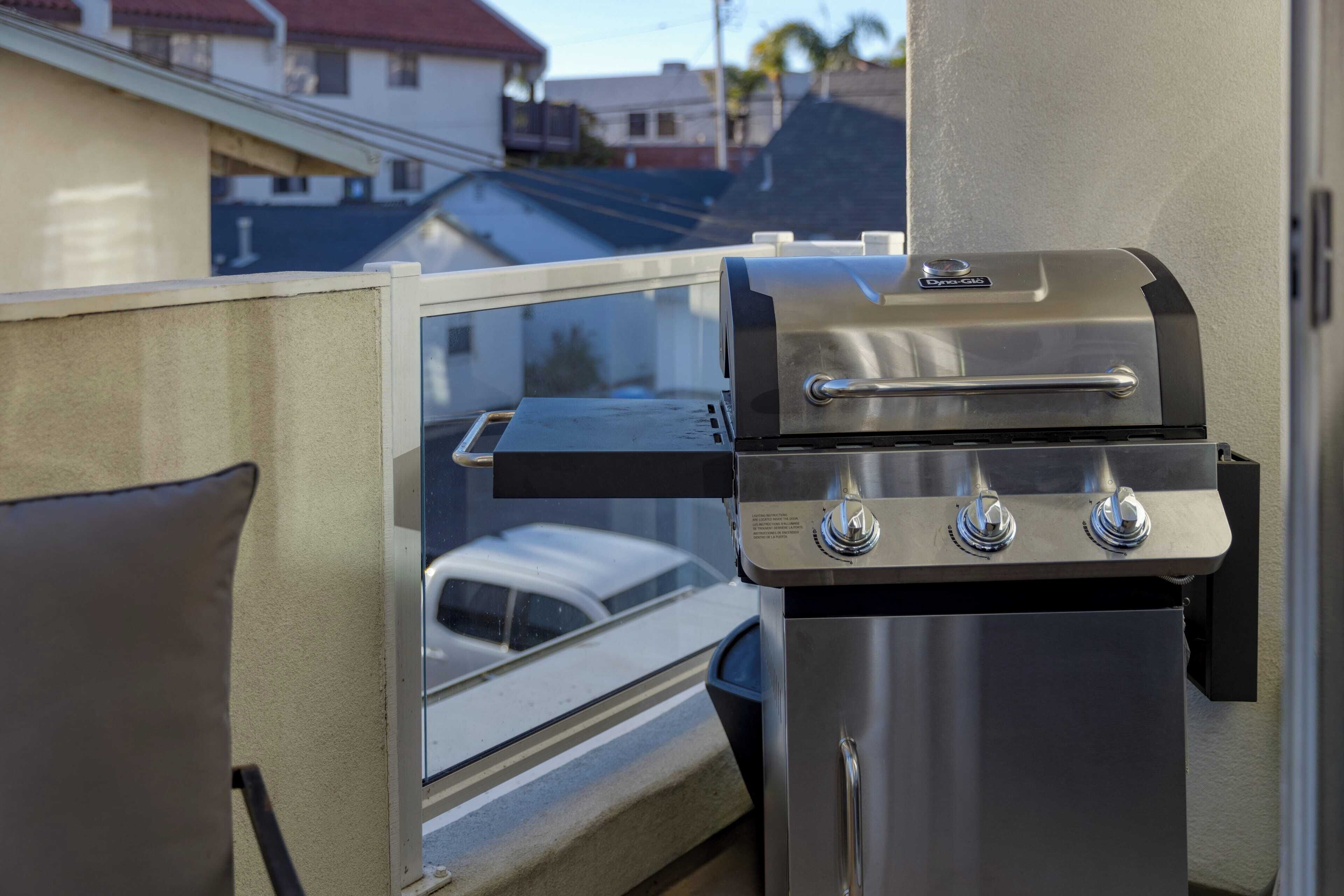 Una parrilla de acero inoxidable unida a un balcón con vistas a una zona residencial.