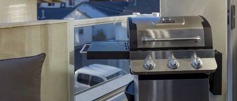 Una parrilla de acero inoxidable unida a un balcón con vistas a una zona residencial.