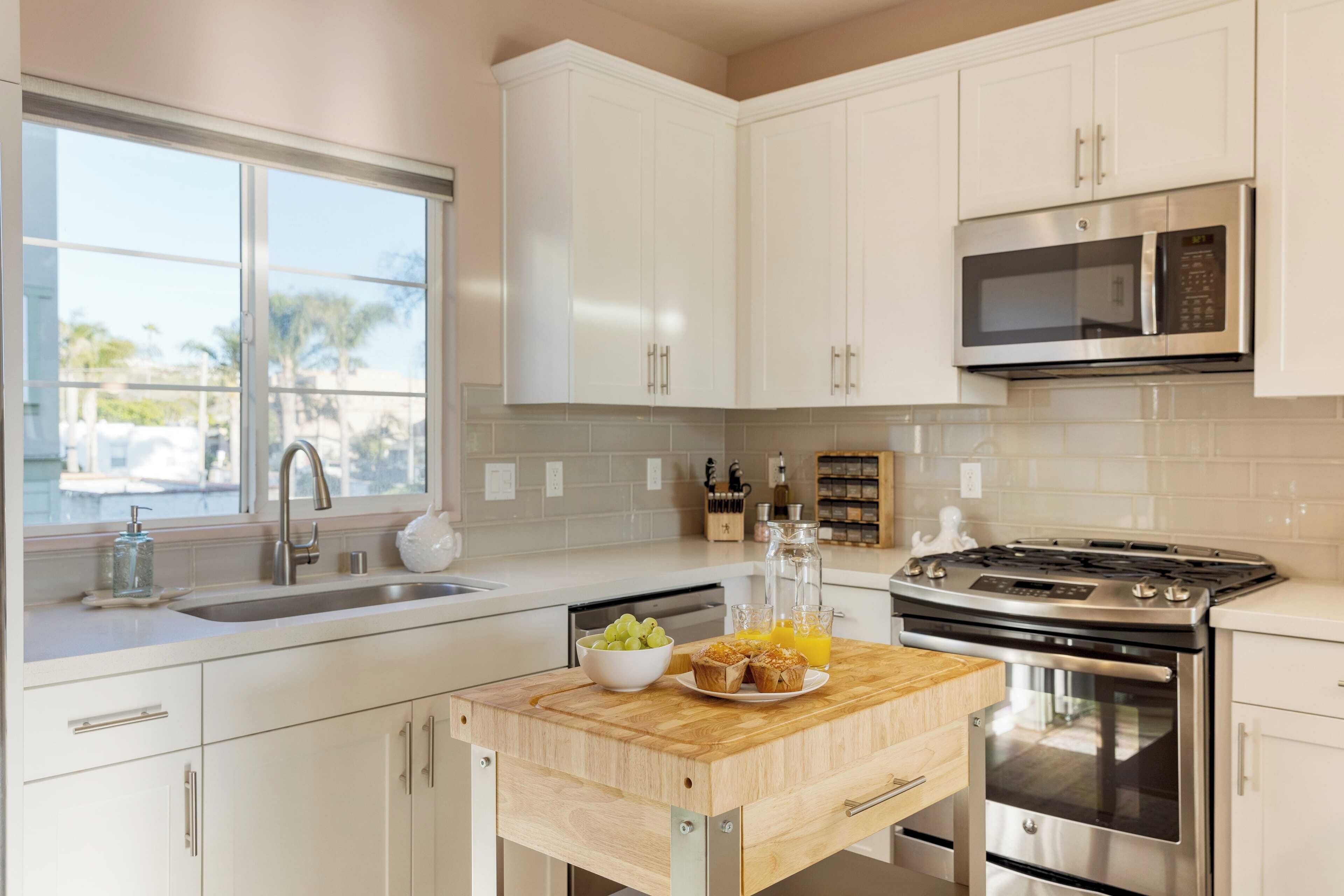 A modern kitchen with white cabinets, a stainless steel microwave, and a gas stove.