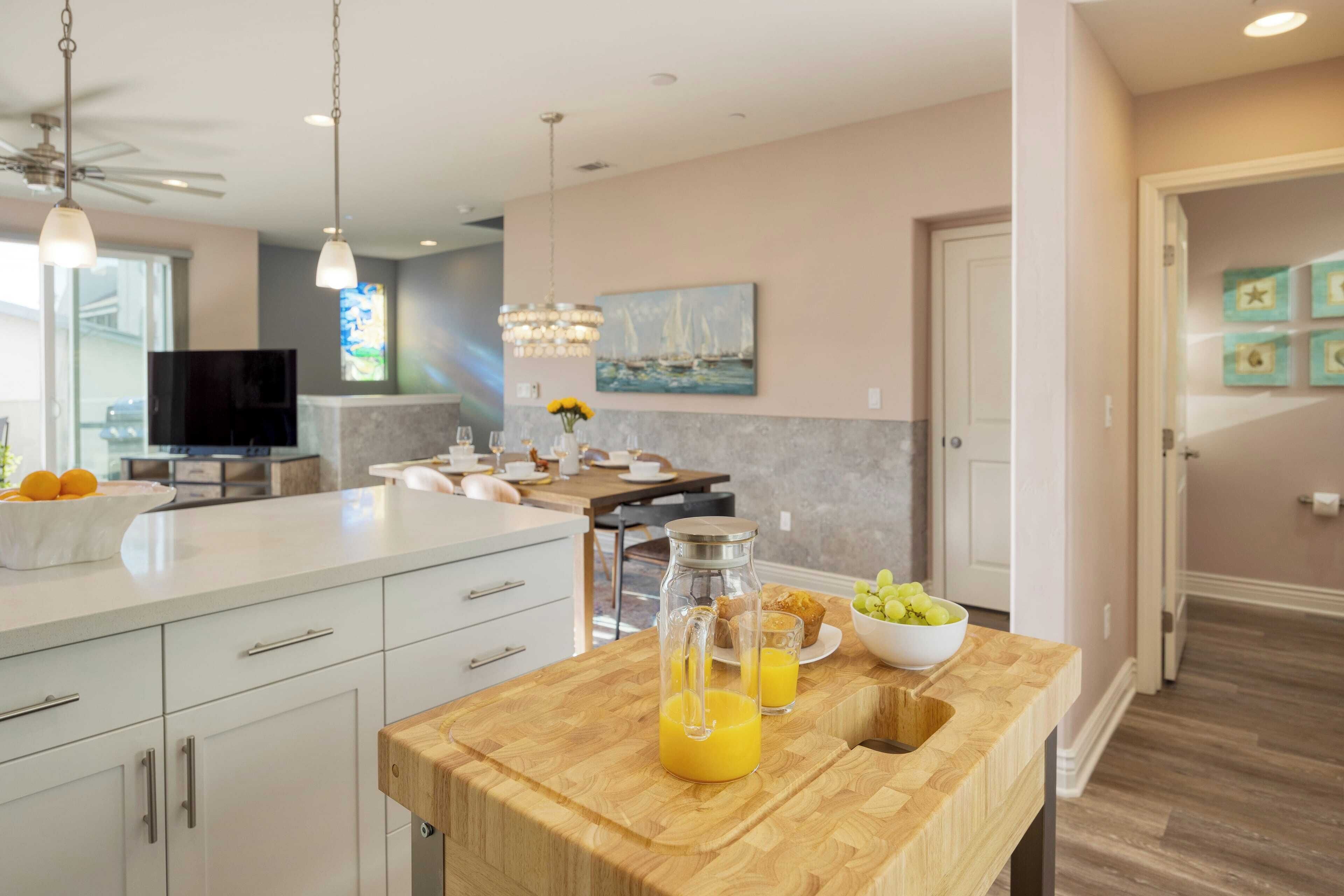 A modern kitchen with a wooden island, a dining area, and a view of the living room.