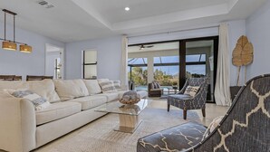 A modern living room with a sofa, armchair, and coffee table. - Brand New & Luxurious, Sunsets, Heated Pool & Spa - Villa Palm Breeze - Roelens (Cape Coral)