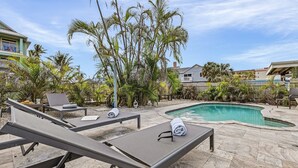 A poolside area with lounge chairs, a swimming pool, and tropical plants. - Gulf Access, Dock, Heated Pool, Across from the Beach - Sea-cluded Bungalow -Roelens (Fort Myers Beach)
