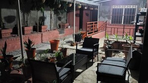 An outdoor patio area with seating, potted plants, and a red railing.