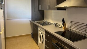 A compact kitchen with a washing machine, a stove, and a sink. - Beautiful 2 Bed Apartment Mar Menor Golf Resort (Torre Pacheco)