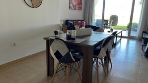 A dining area with a wooden table, black and white chairs, a clock on the wall, and a painting above the table. - Beautiful 2 Bed Apartment Mar Menor Golf Resort (Torre Pacheco)