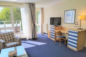 A hotel room with a bed, a desk, a chair, a television, and a window with curtains.