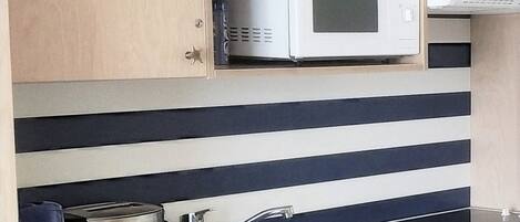 A kitchen with a microwave, toaster, and sink.