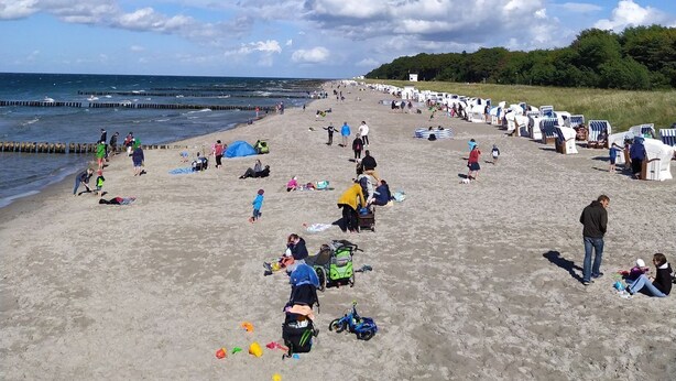 Une plage avec des gens, des chaises de plage et un ciel dégagé.
