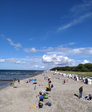 Een strand met mensen, ligstoelen en een heldere lucht.