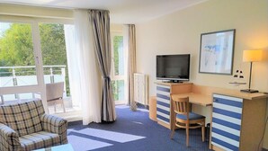 Une chambre d’hôtel équipée d’un lit, d’un bureau, d’une chaise, d’une télévision et d’une fenêtre avec des rideaux.