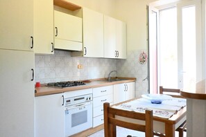 Una cocina con armarios blancos, una estufa, un horno y un fregadero.