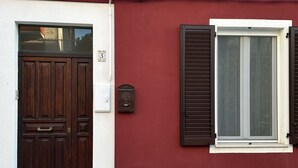 A building with a dark wooden door, a mailbox, and a window with shutters. - P044 - Porto Recanati, comfortable three-room apartment in the historic center (Porto Recanati)