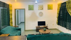 A living room with a sofa, a coffee table, a TV, and artwork on the wall.
