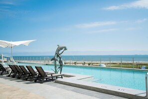 Une piscine avec des chaises longues et une statue de dauphin.