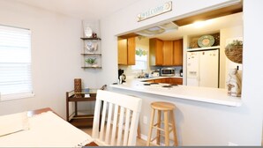 A modern kitchen with wooden cabinets, a white countertop, and a 'WELCOME' sign above the door. - Sunny Daze Walk to Beach 2 Decks Pet Friendly (Galveston)