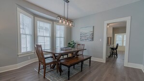 A dining area with a wooden table, four chairs, a bench, and a hanging light fixture.