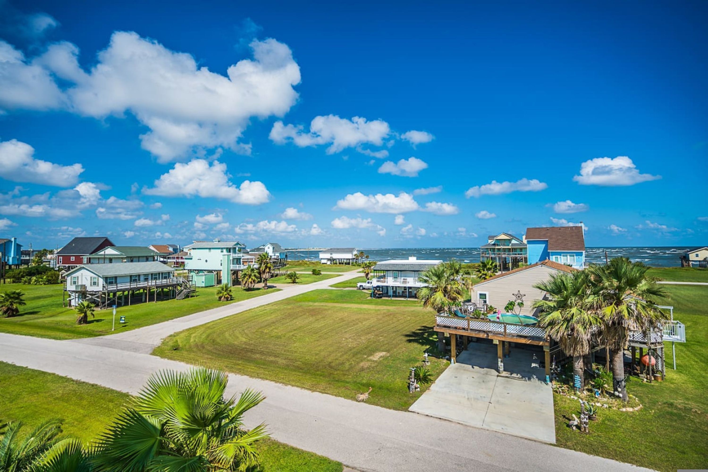 A coastal residential area with houses, a clear sky, and a view of the ocean.