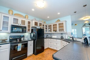 Enjoy cooking in this well-equipped kitchen with a stainless steel refrigerator, oven, and microwave, set against a light wood floor.