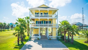 A two-story building with a balcony, surrounded by palm trees and a clear sky. - Serenity By the Sea - Great Views in Treasure Isla (Freeport)