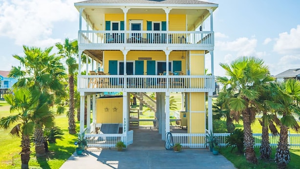 A two-story building with a balcony, surrounded by palm trees. - Serenity By the Sea - Great Views in Treasure Isla (Freeport)