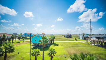A coastal residential area with houses, palm trees, and a clear sky.