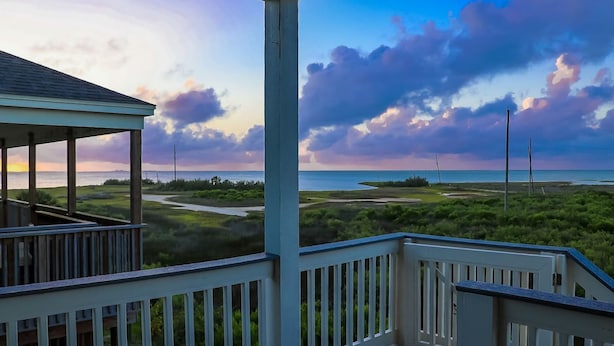 A wooden deck with a view of a coastal landscape, including grassy areas and a body of water. - Great bay Views and a Pool in Isla Del Sol (Galveston)