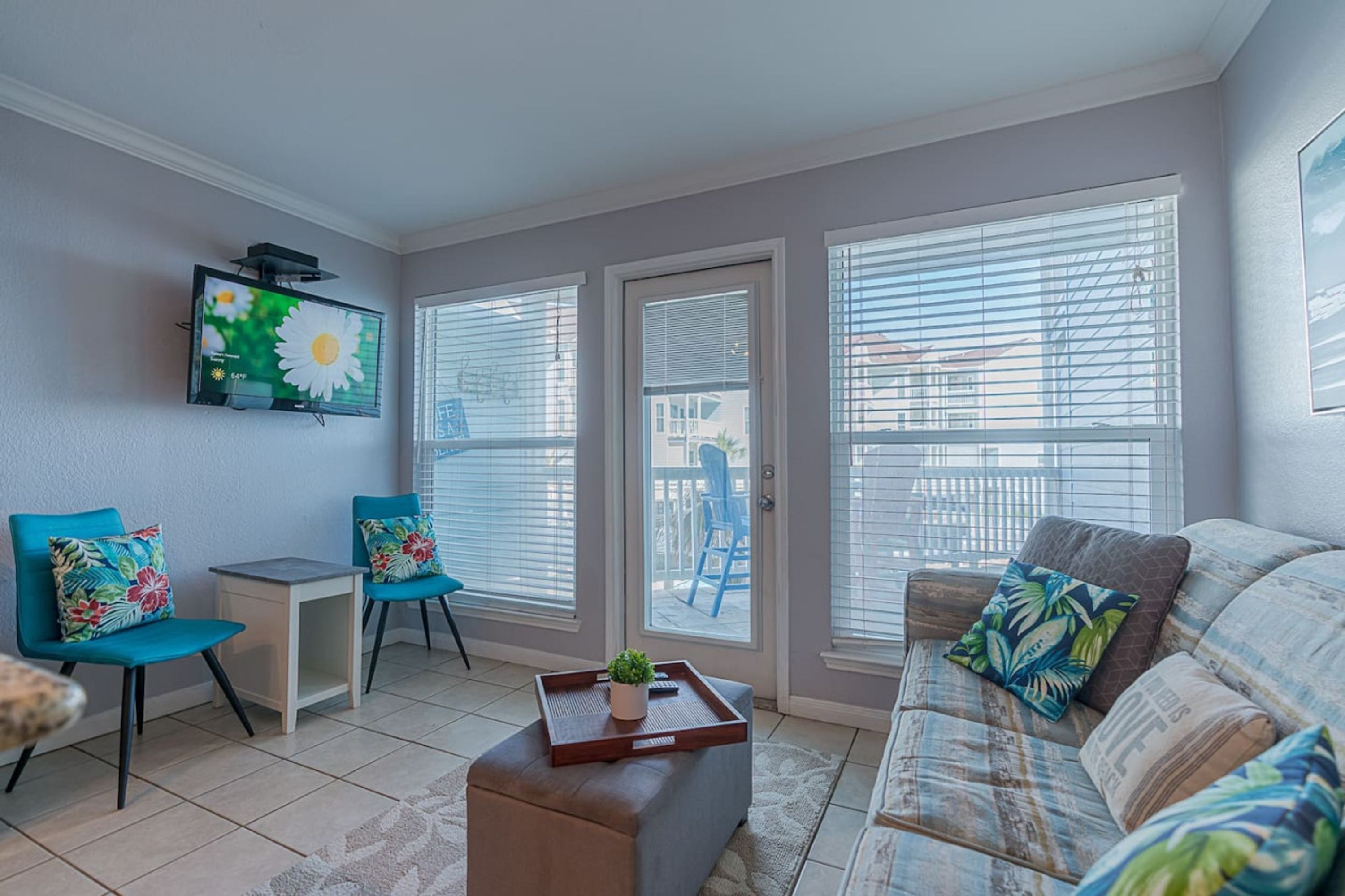 A living room with a sofa, two chairs, a small table, and a TV mounted on the wall.