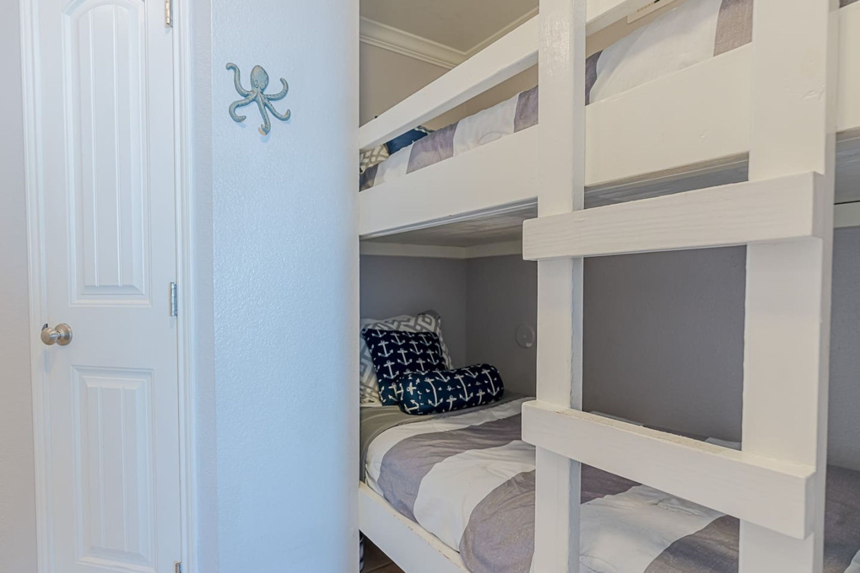 A bunk bed room with a white door and a wall-mounted octopus decoration.
