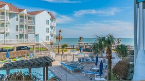 Een strandhotel met een zwembad, ligbedden en uitzicht op de oceaan.
