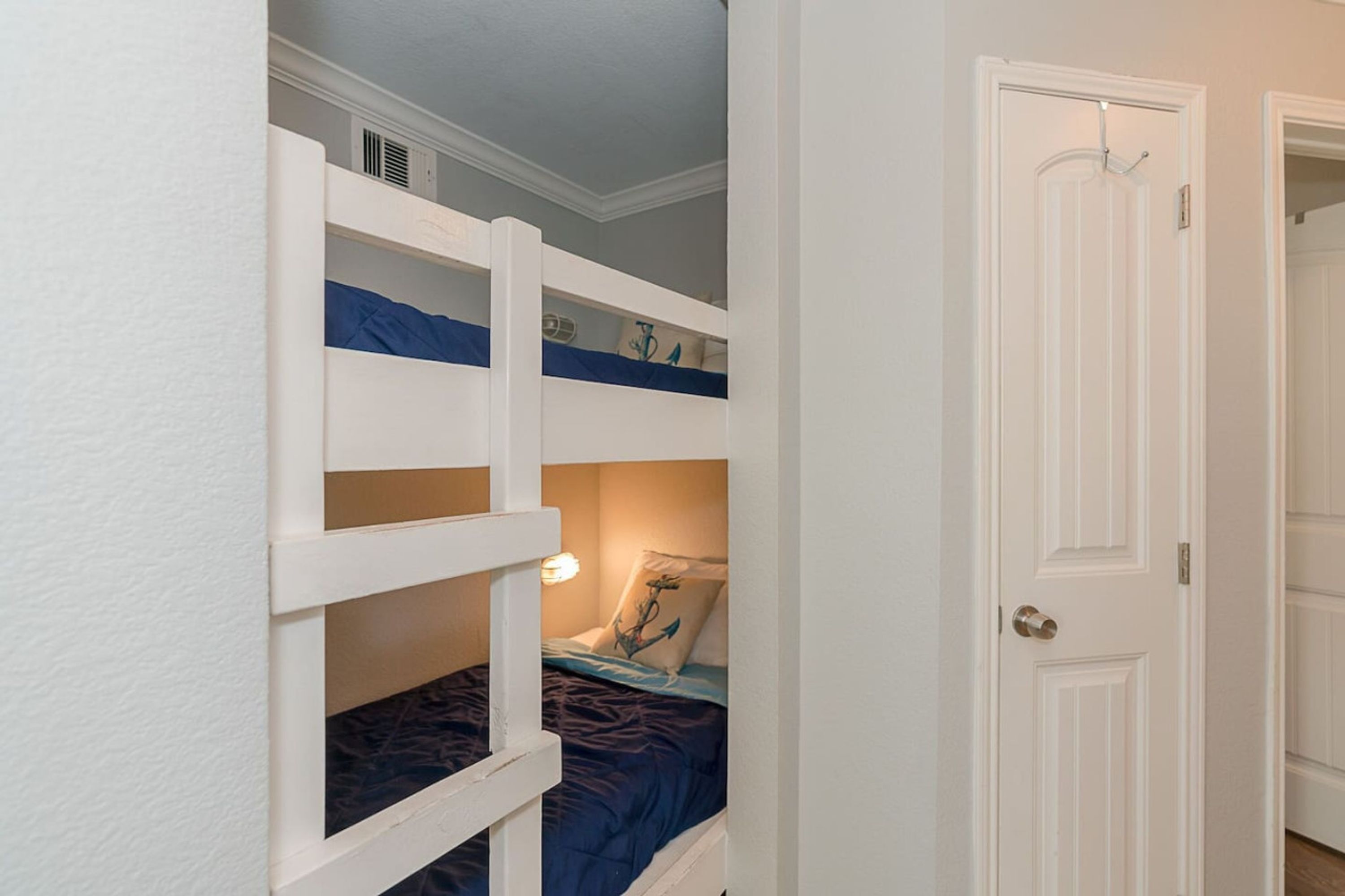 A room with bunk beds, a door, and a wall-mounted heater.