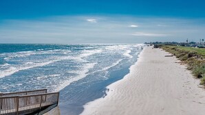 A beach with a wooden walkway along the shore. - Get Beach Dazed in Galveston (Galveston)