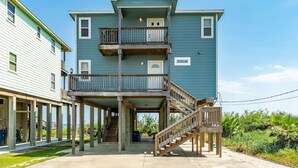 A two-story building with a balcony on the upper floor, wooden railings, and a staircase leading to the entrance. - Superb Home With Private Walkover to Beach (Freeport)