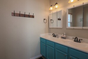 Une salle de bain avec deux lavabos, un miroir et un porte-serviettes.