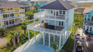 A multi-story coastal house with a balcony, surrounded by palm trees and other houses. - Unforgettable Vacation Getaway in Treasure Island (Freeport)