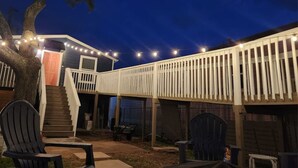 A backyard with a wooden deck, a staircase leading to a house, and outdoor seating. - Vacation in Style at the Beach (Galveston)