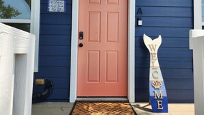 A blue house with a peach-colored door, a welcome sign, and a mailbox. - Vacation in Style at the Beach (Galveston)