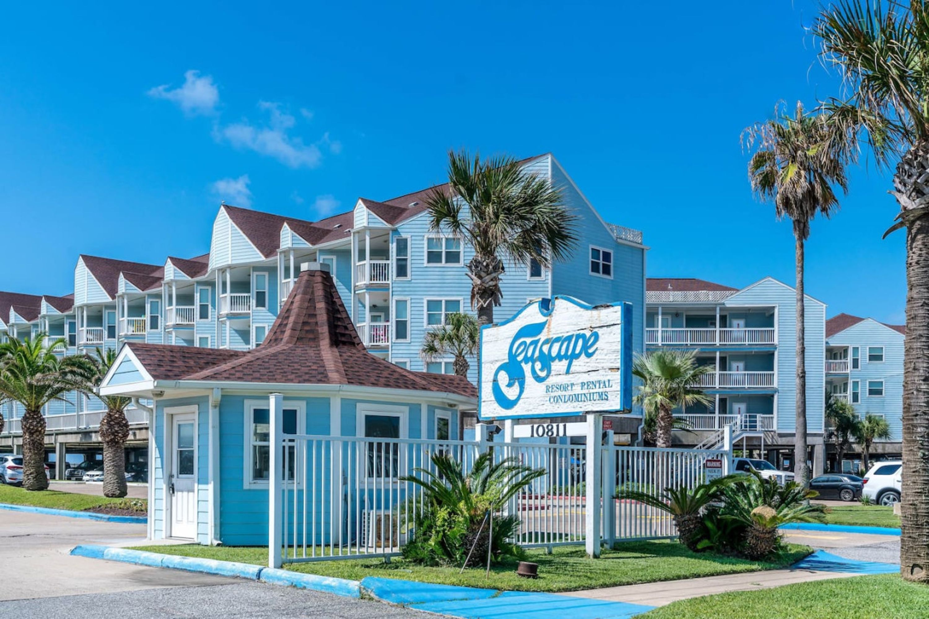 Un complexe hôtelier avec une enseigne indiquant « Teescape Resort Rental Condominiums » et une petite maison d’hôtes.
