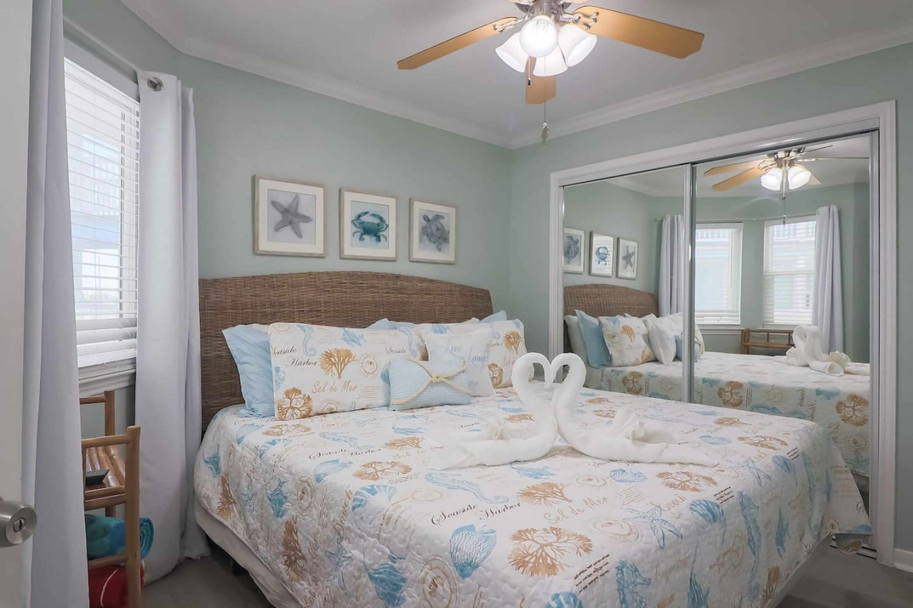 A bedroom with a large bed, a ceiling fan, and a mirror.