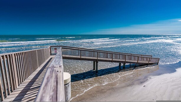 A wooden boardwalk leading to the beach with a clear view of the ocean.