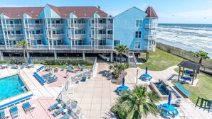 Ein Strandhotel mit mehreren Balkonen, einem Schwimmbad und Sitzbereichen im Freien.