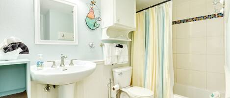 A bathroom with a sink, mirror, toilet, and shower curtain.