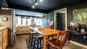 Una cocina con una mesa de madera, sillas, un refrigerador y un microondas.
