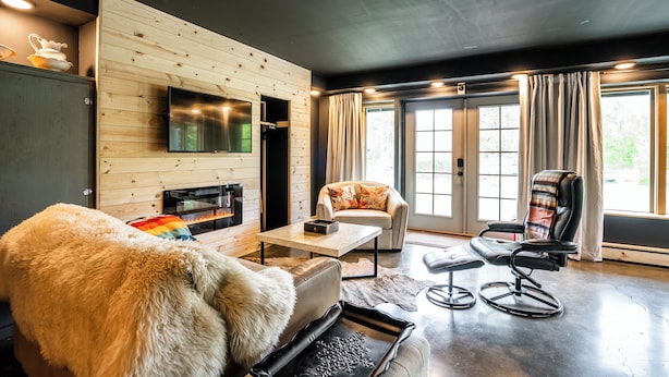 Una sala de estar moderna con chimenea, un sofá, un sillón y un televisor montado en la pared.