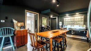 Una cocina con mesa de madera, sillas, microondas y pileta.