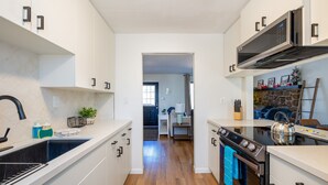 Een moderne keuken met witte kasten, een roestvrijstalen fornuis en een magnetron.