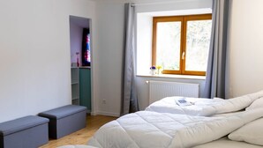 A bedroom with two beds, a window with curtains, a radiator, and a small shelf with items. - 2 Chambres table d'hôtes in the countryside le nid qui danse near Vesoul 2 to 6 pers. (Baignes)