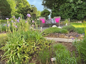 Un jardin avec une table et des chaises, une statue et différentes plantes.