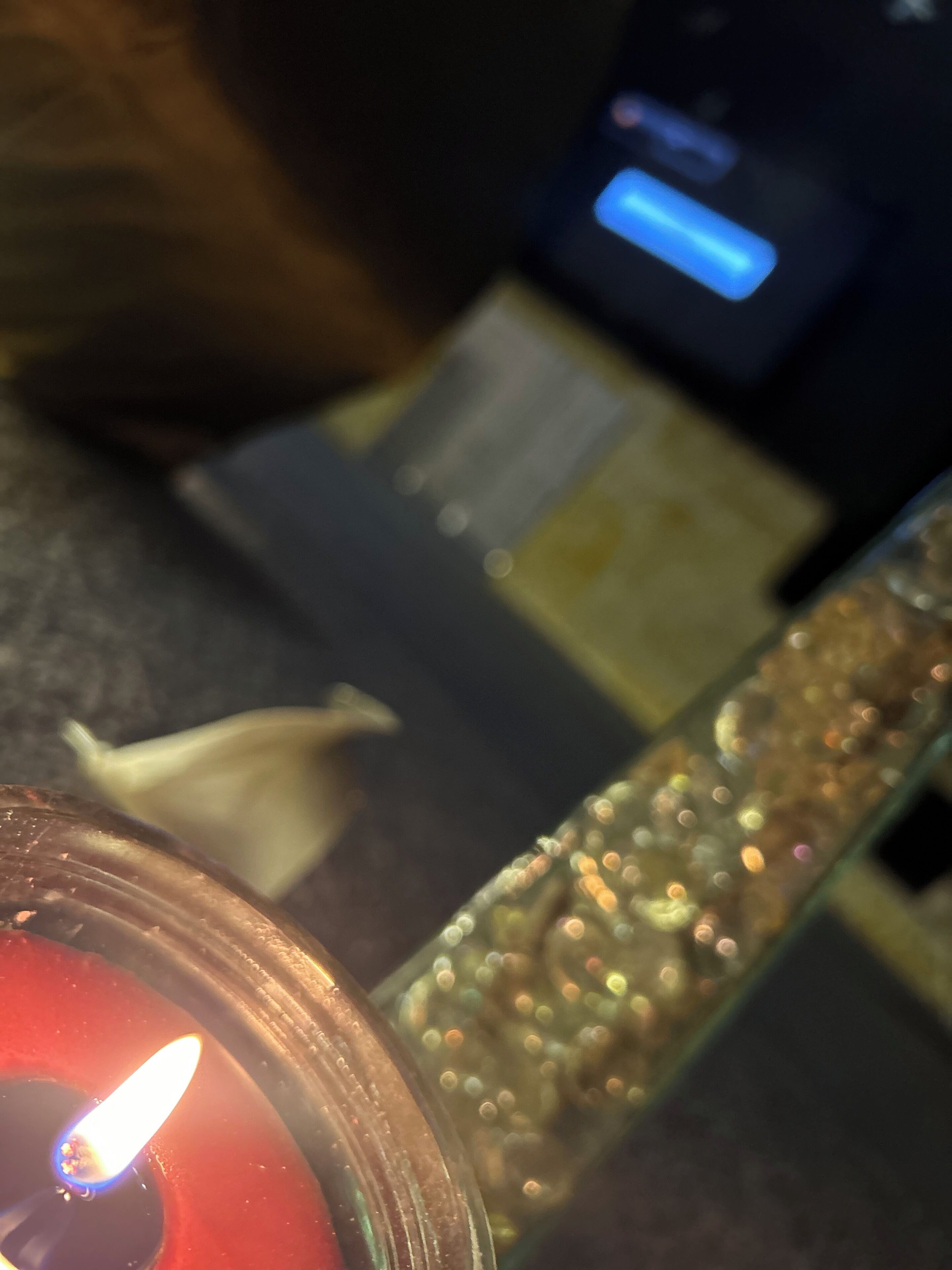 Ein Detailaufnahme einer Kerze in einem Glasgefäß mit strukturierter Oberfläche.
