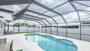 Een overdekt zwembad met een golvend ontwerp, omringd door een witte hek en een pergola.